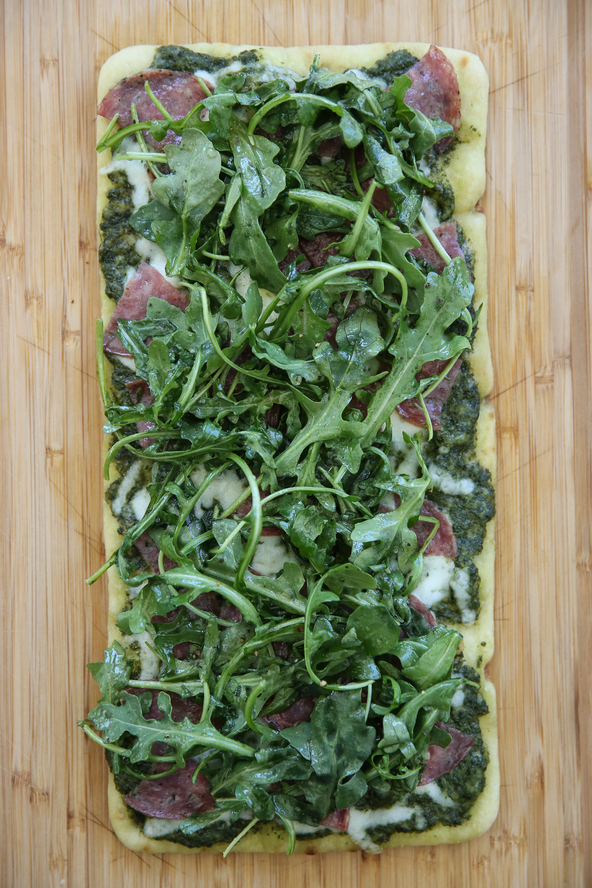 Cooked flatbread with salami and cheese and greens