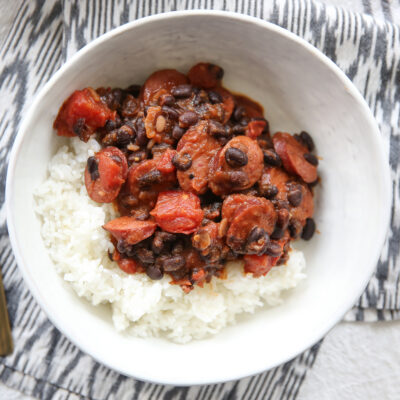 black bean and sausage over rice in a white bowl