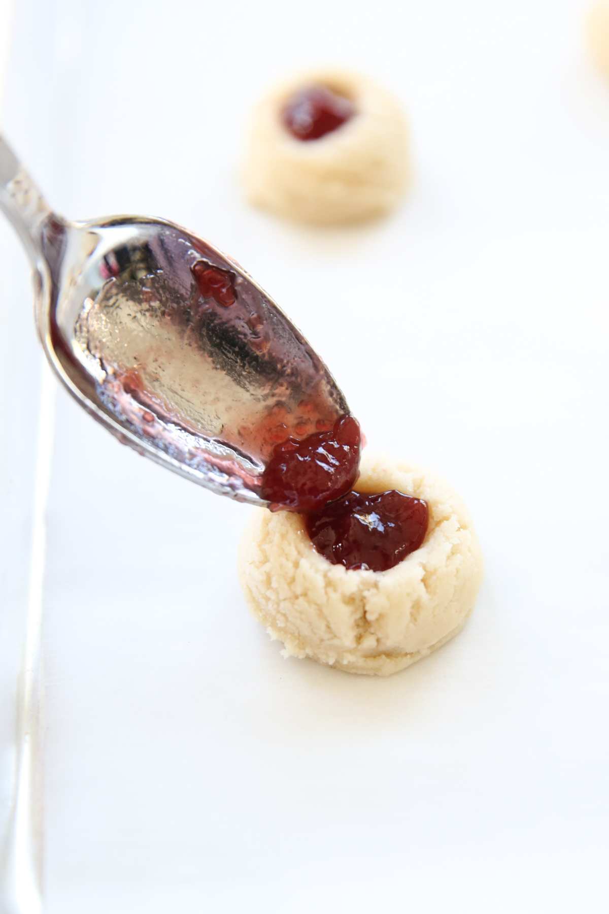 filling thumbprint cookies with jam
