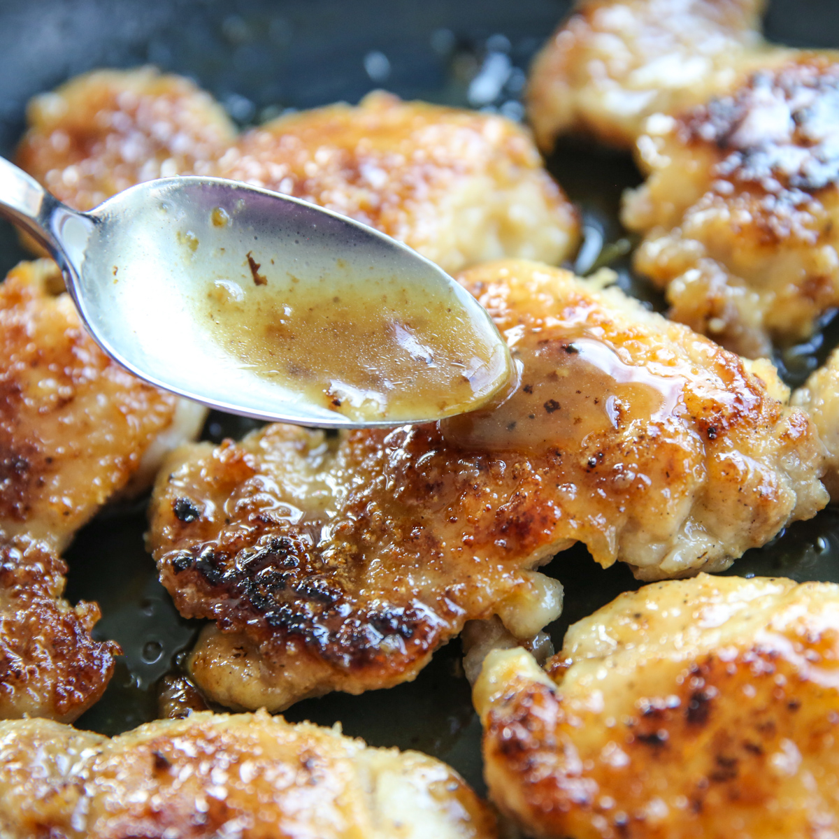 drizzling sauce over browned chicken thighs