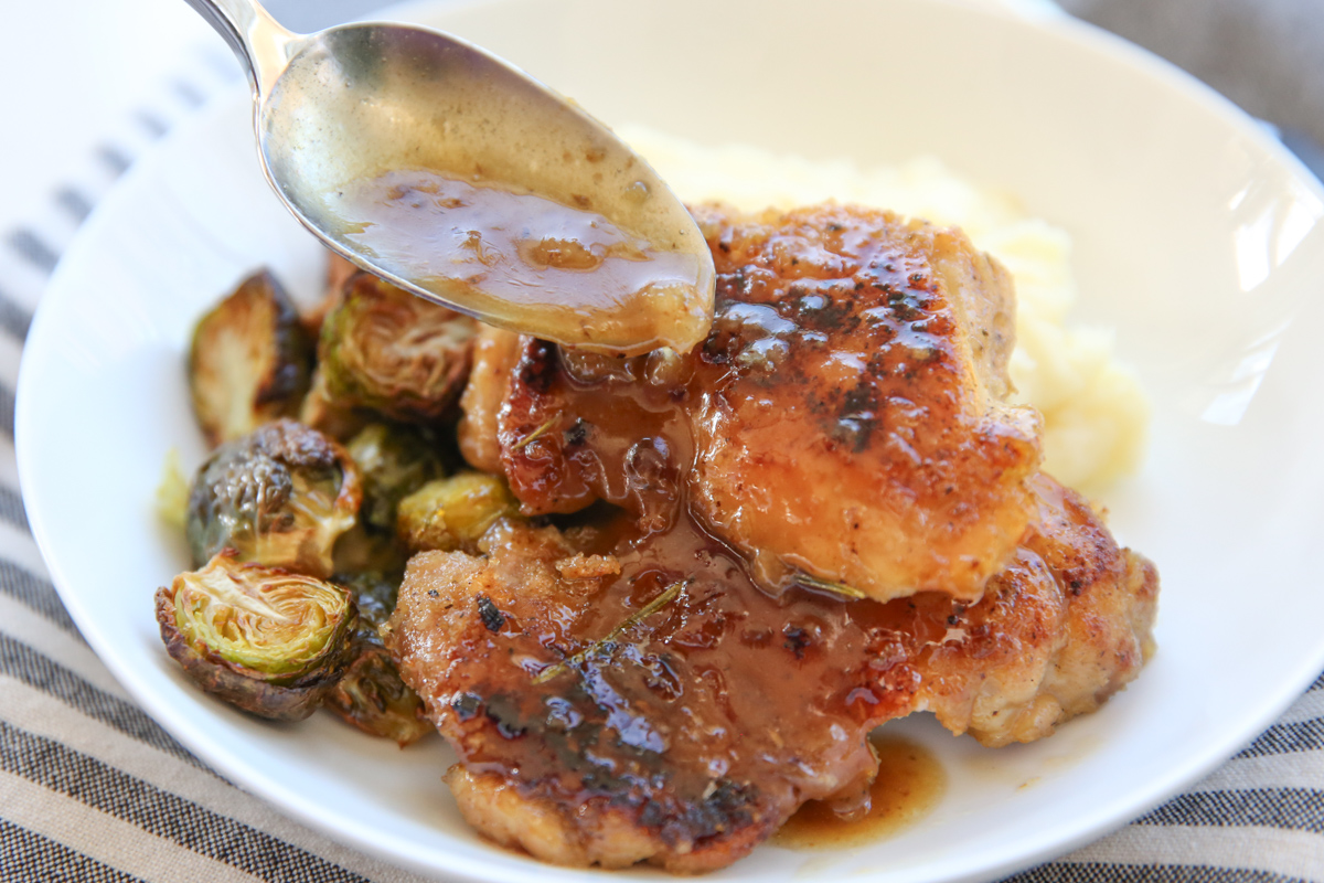 Drizzling sauce over Apple Cider Chicken Thighs 