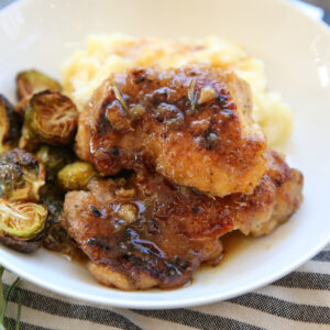 glazed maple cider chicken on a plate with potatoes and veggies