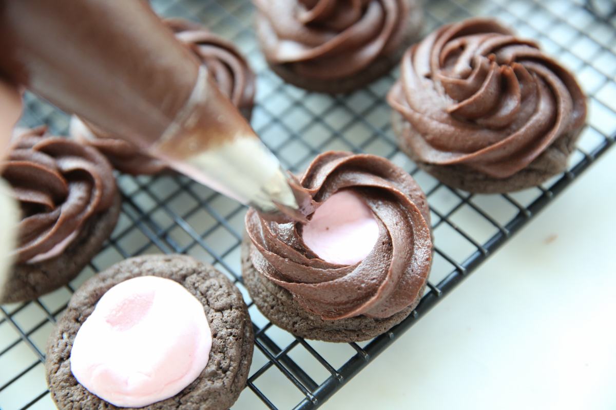 piping frosting on chocolate cookies
