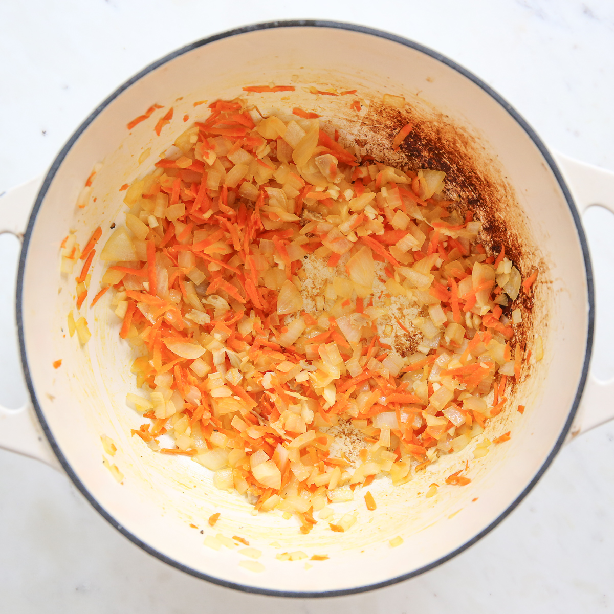 Carrots and onions sautéing in a pot.