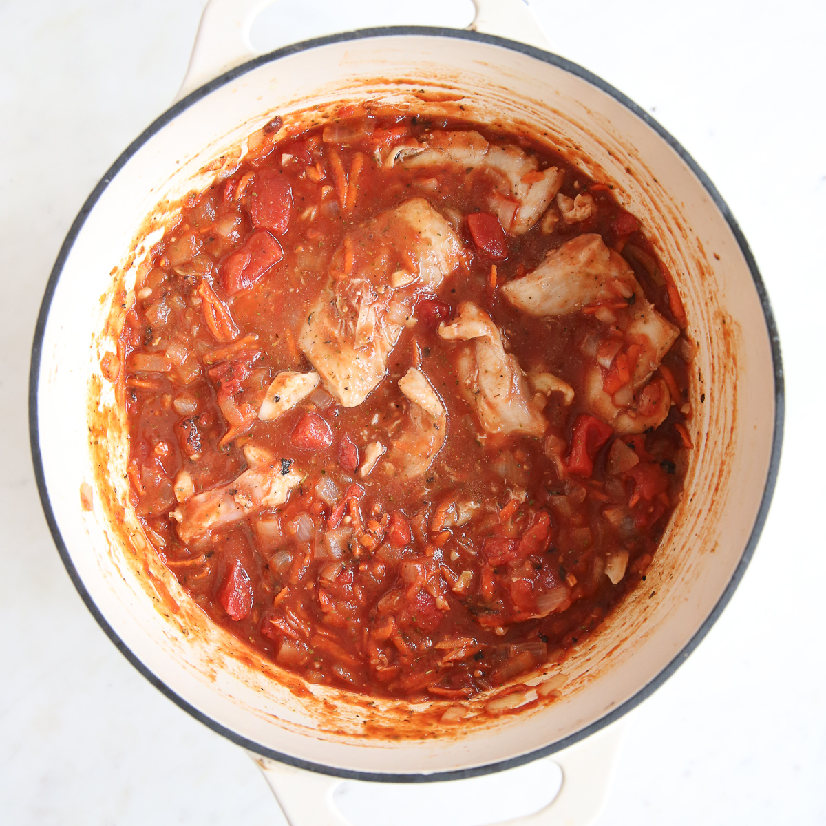 Fresh chicken thighs are added to pot to simmer with carrots and onions.