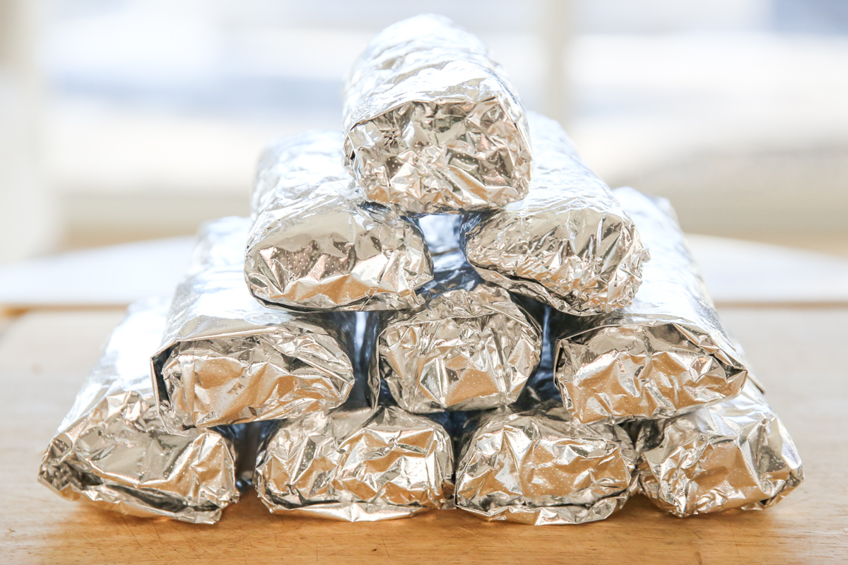 burritos wrapped in foil stacked in a pile