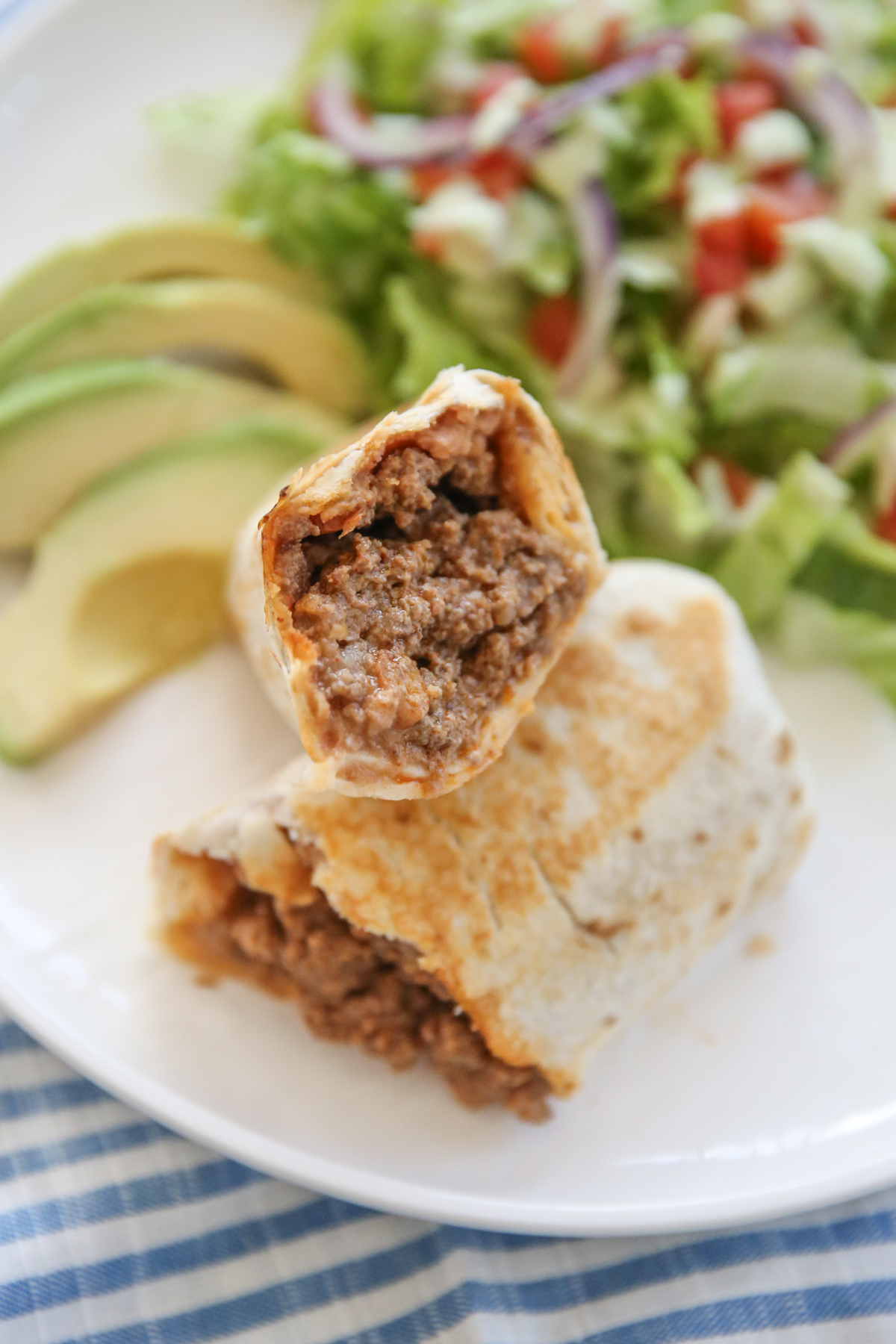 burrito cut in half stuffed with bean, beef, and cheese. 