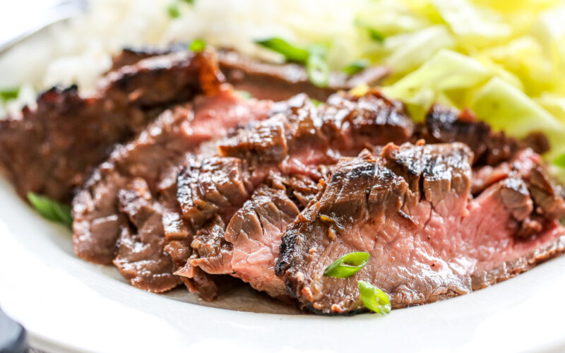 Sliced Ginger Soy Flank Steak on a plate with rice and cabbage