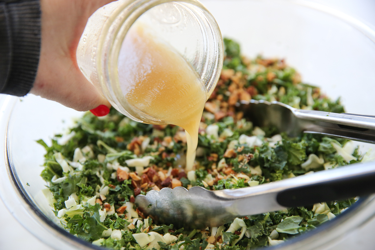 pouring dressing from a mason jar onto kale salad