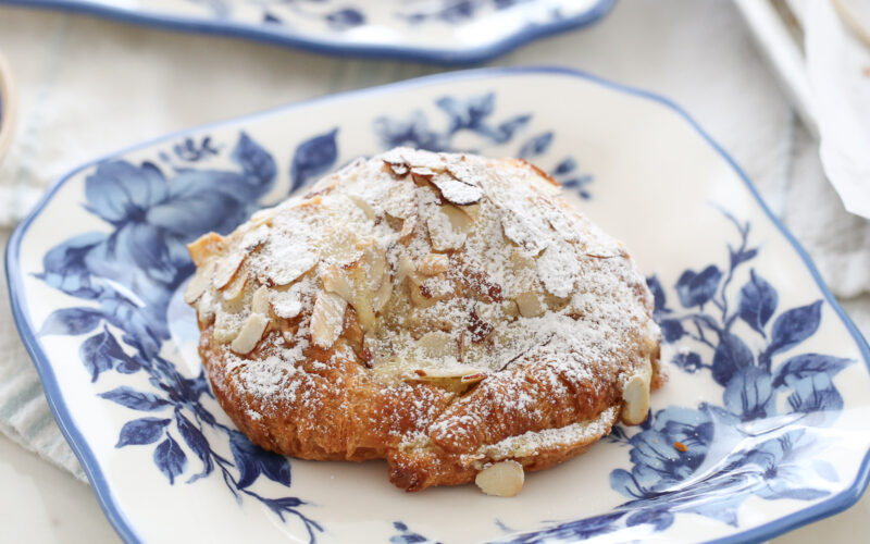almond croissant dusted in powdered sugar on a blue and white plate