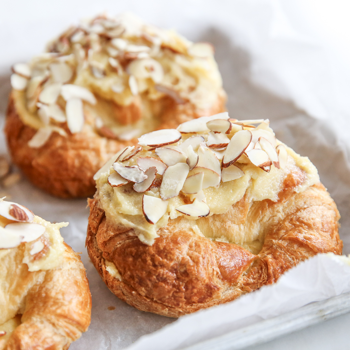 croissants on a baking sheet covered with almond cream and sliced almonds