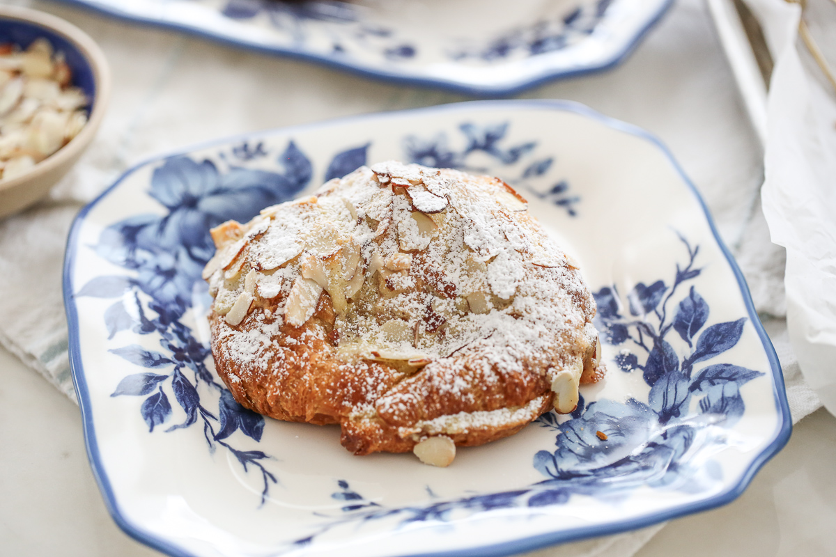 almond croissant dusted in powdered sugar on a blue and white plate