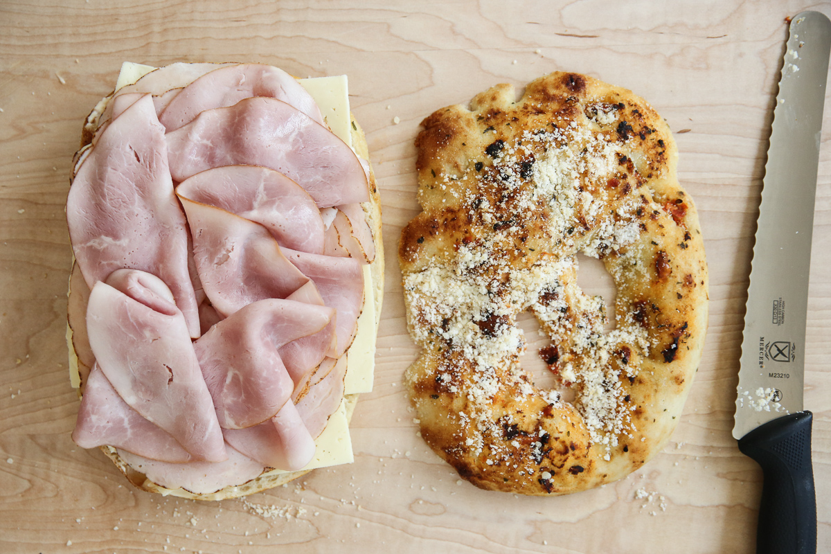 assembling an Italian grinder sandwich on a cutting board