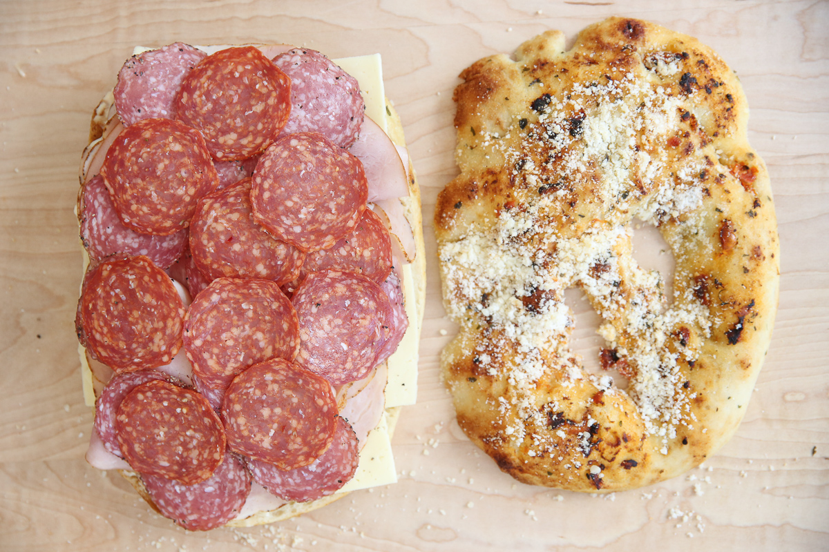 assembling an Italian grinder sandwich on a cutting board
