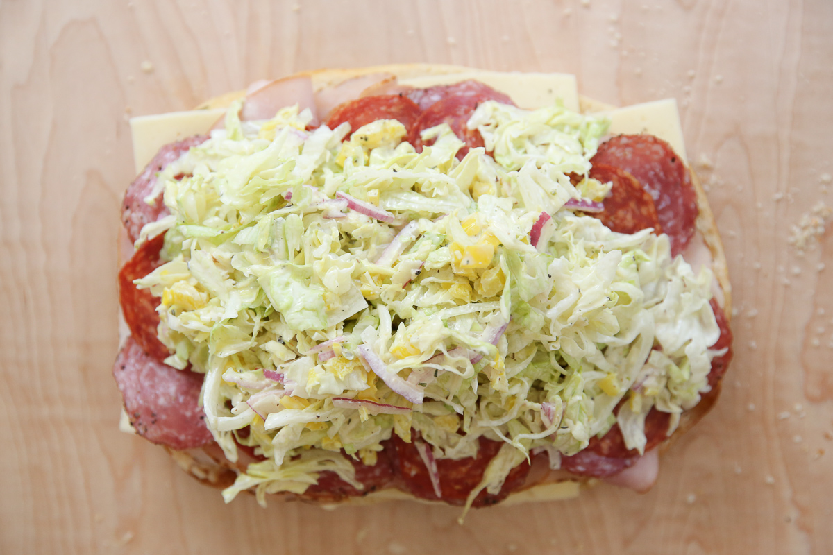 assembling an Italian grinder sandwich on a cutting board