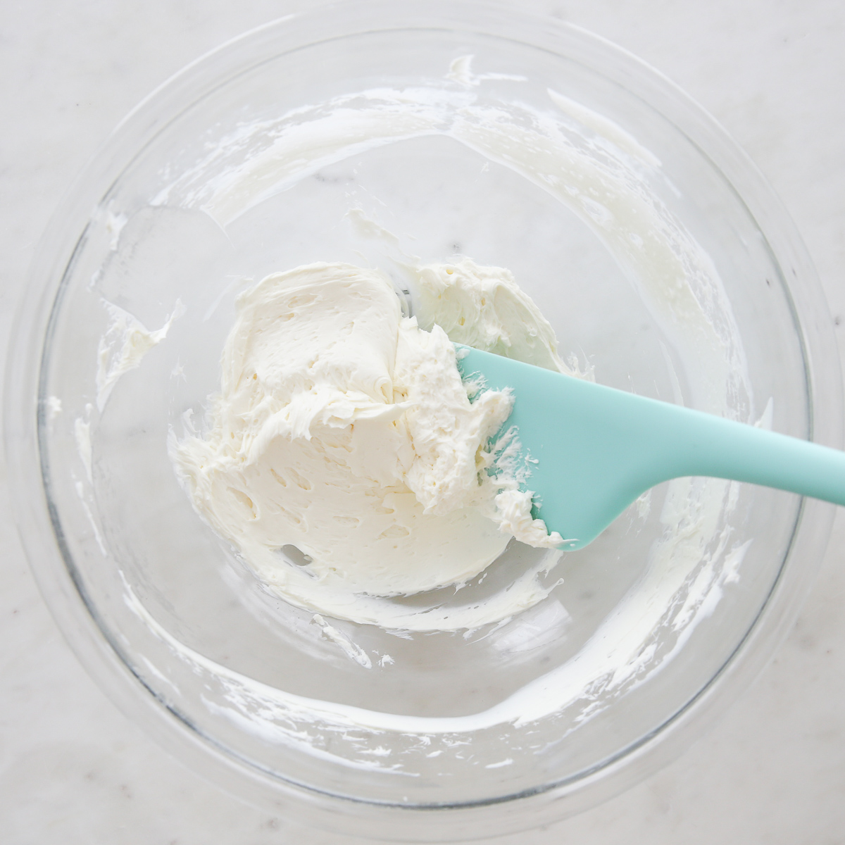 cream cheese in a glass bowl with a spatula