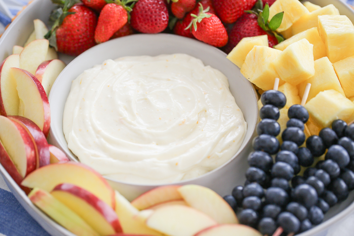 a bowl of fluffy fruit dip surrounded by fresh fruit