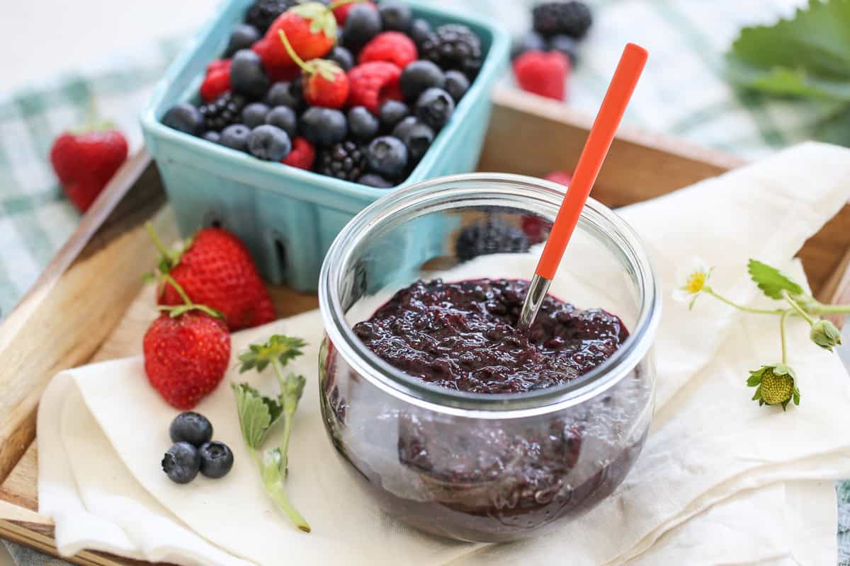 glass jar full of chia seed jam surrounded by berries