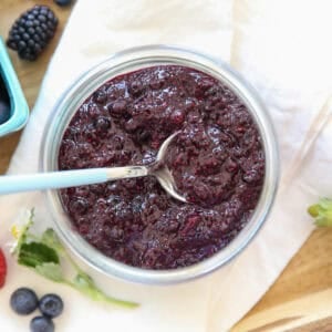 blueberry chia jam in a glass jar with a spoon in it