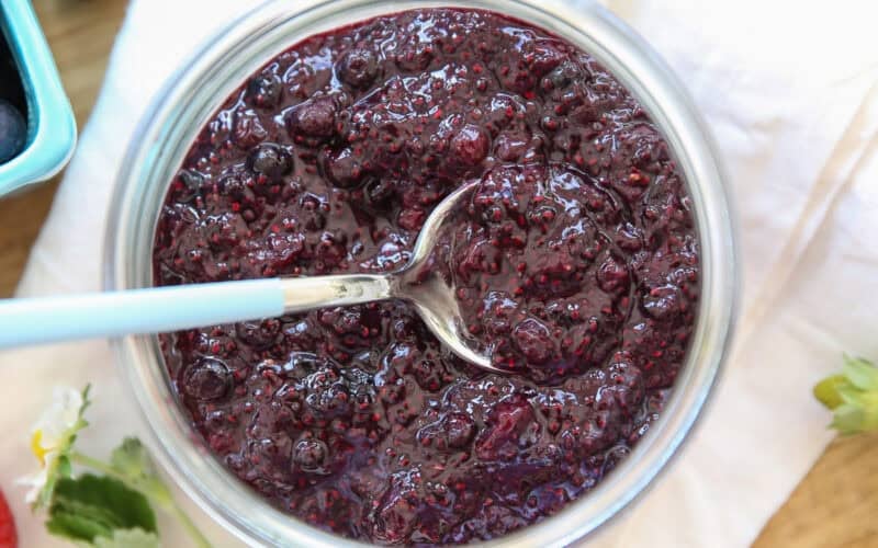 blueberry chia jam in a glass jar with a spoon in it