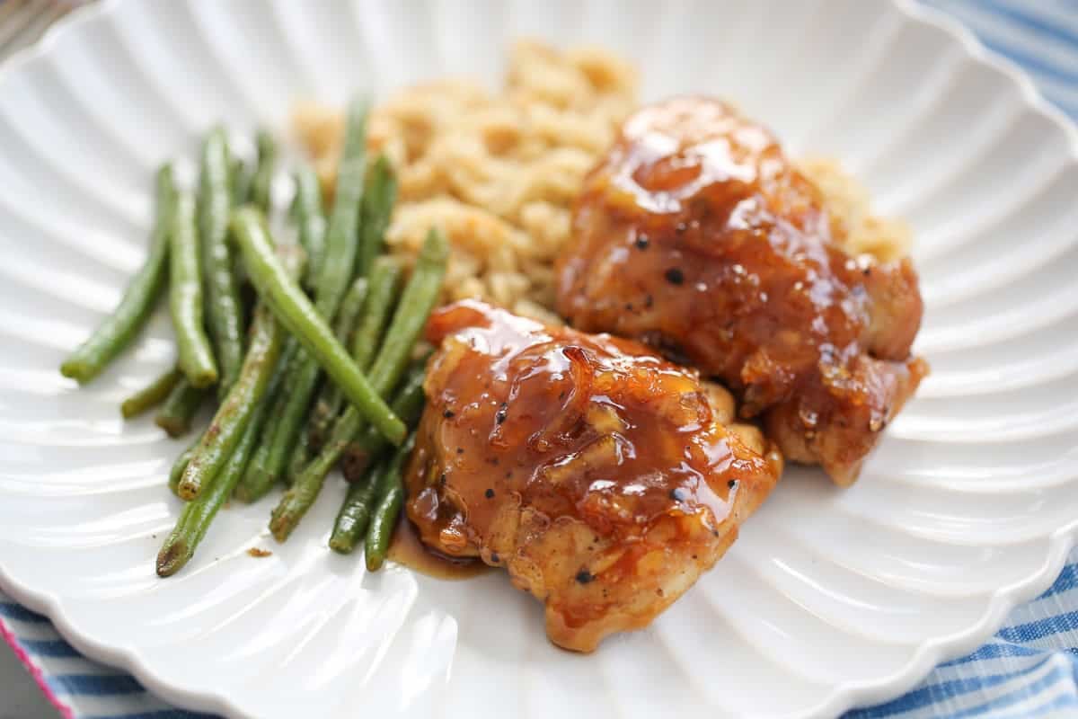white plate with chicken thighs, rice pilaf, and green beans