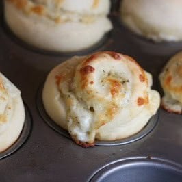 A cheesy Garlic Bread Swirl, freshly baked in a muffin tin.