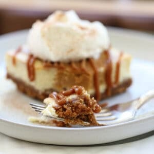 single serving cheesecake square with caramel and whipped cream with a bite taken out