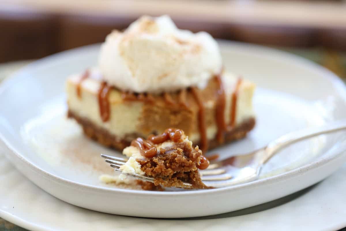 single serving cheesecake square with caramel and whipped cream with a bite taken out