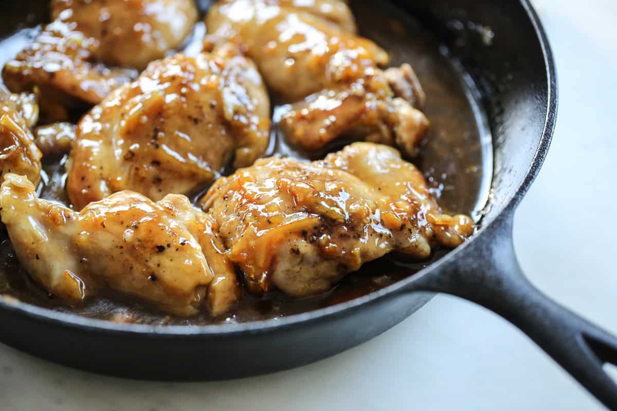 glazed orange chicken thighs in a cast iron pan