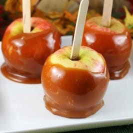 3 apples, dipped in honey caramel, on a white plate.