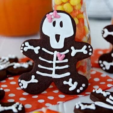 A cute chocolate gingerbread man shaped cookie decorated with a white icing skeleton.